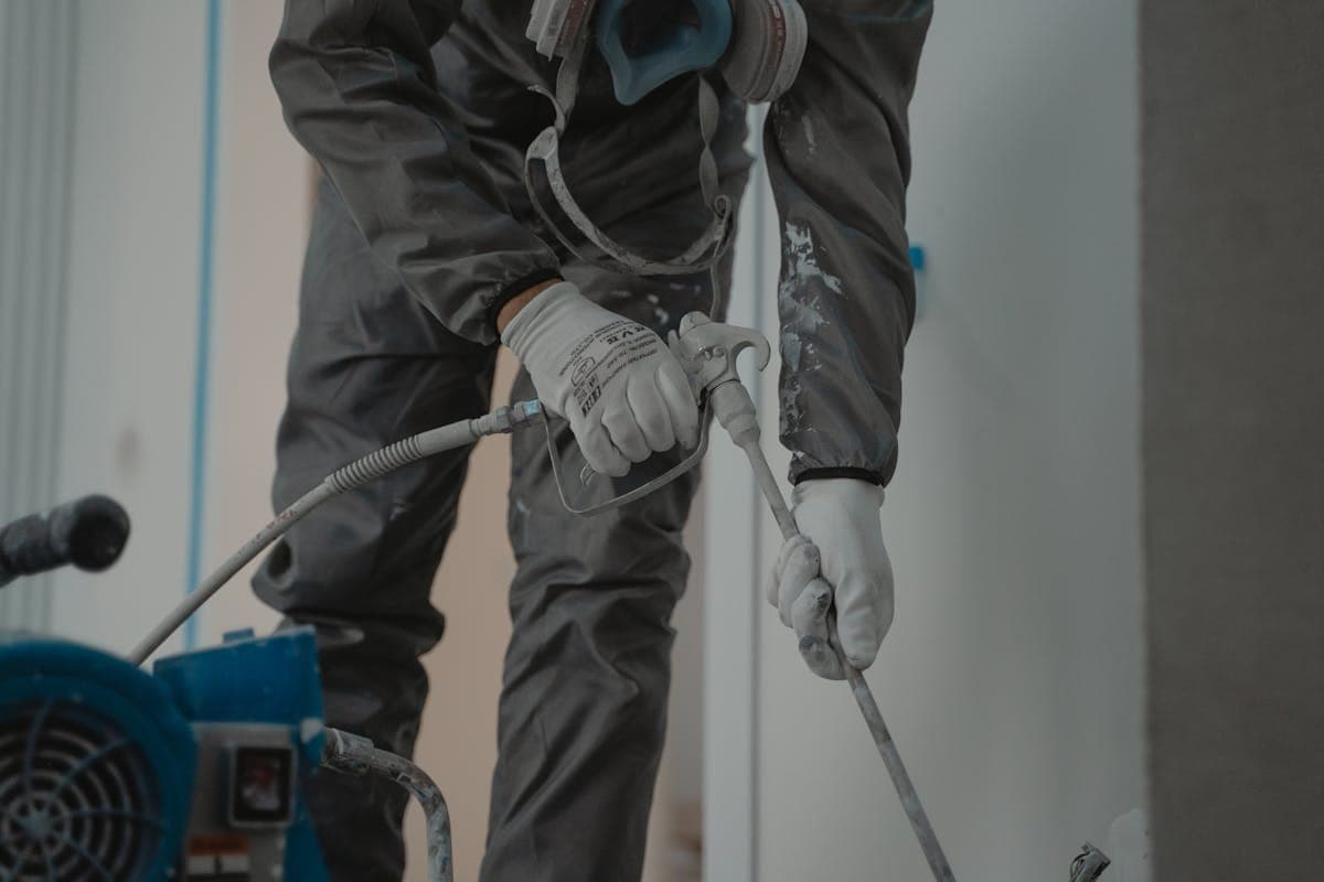 Worker in protective gear performing indoor water damage restoration