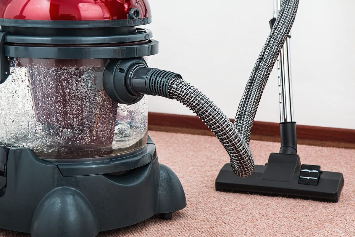 Wet extraction vacuum pulling water from a residential carpet during water damage restoration