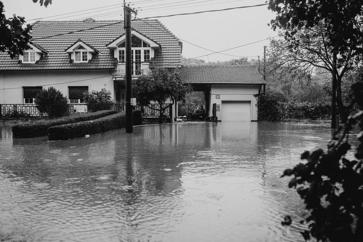 Flooded residential street with standing water after heavy rain showing the type of water damage that requires emergency flood cleanup and restoration services