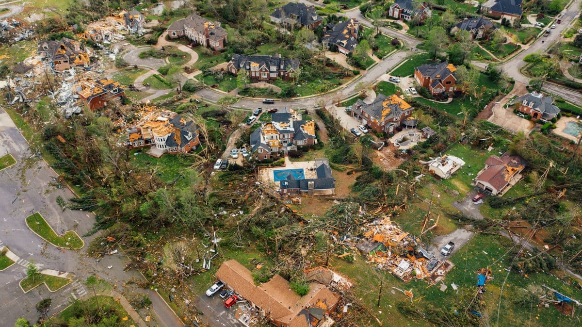 Aerial view of a Dallas residential neighborhood with damaged roofs and downed trees after a severe summer thunderstorm
