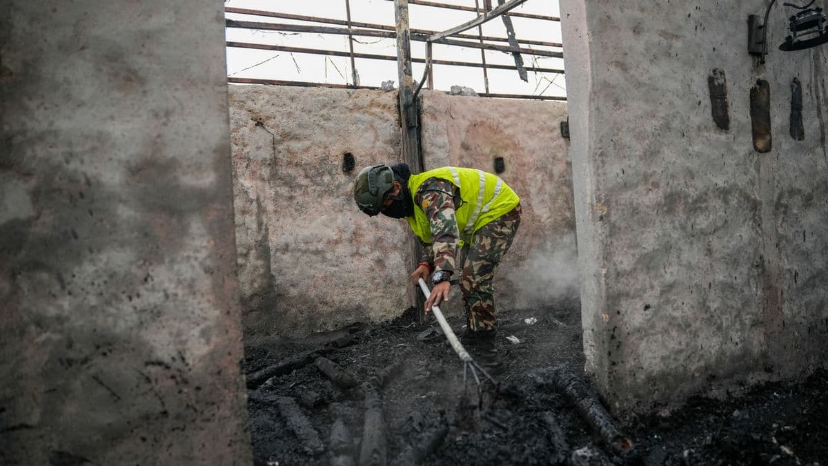 Professional fire and smoke damage cleanup worker in protective gear cleaning soot and debris from a DFW home after a house fire, showing the type of protective equipment and cleaning methods used in smoke damage restoration
