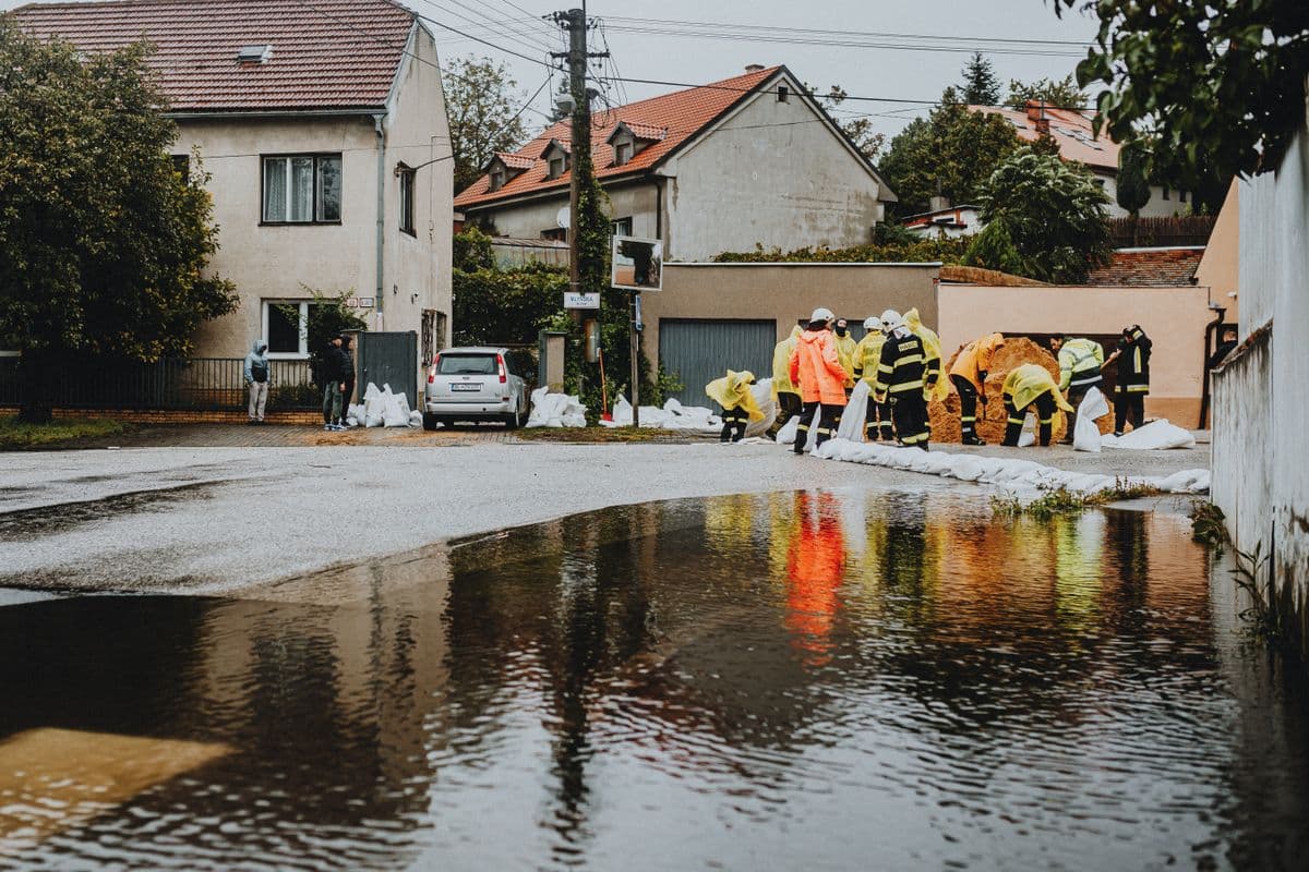 Emergency responders in reflective gear addressing floodwaters on a residential street, representing the type of flood damage situation that requires professional restoration in DFW