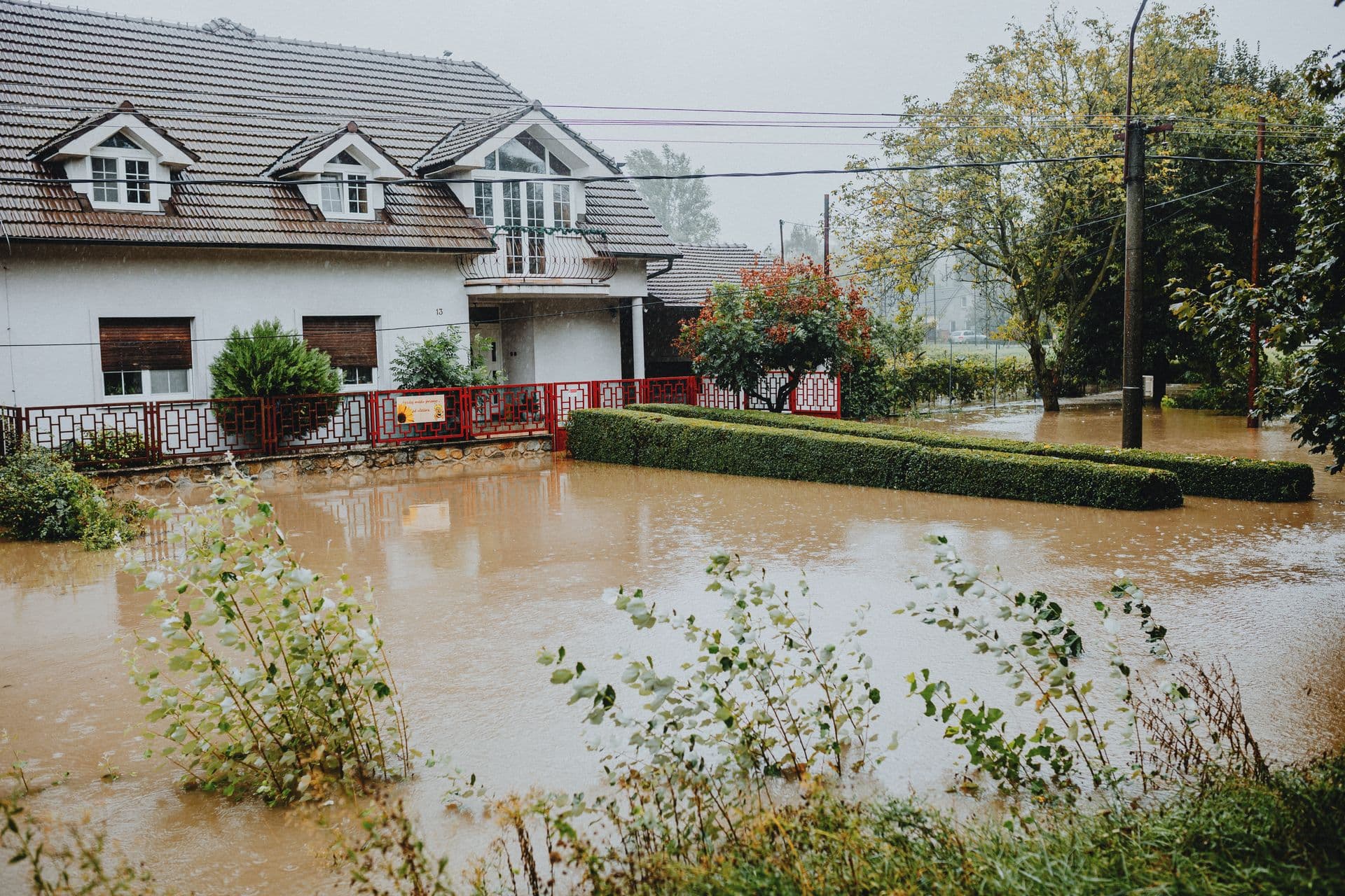 Flooded residential area protected by red flood barriers during heavy rain in Fort Worth, Texas, showing emergency response vehicles and equipment deployed along the Trinity River corridor