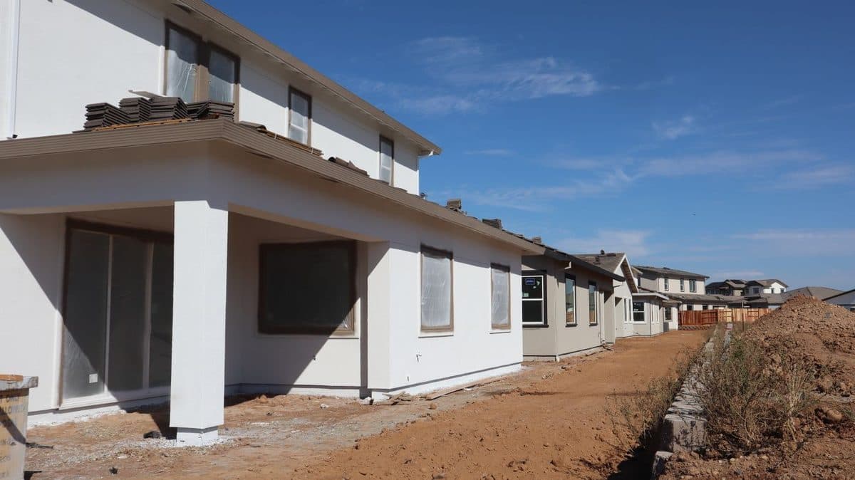A row of newly built North Texas homes on bare red clay, the kind of tight new construction that can trap moisture and fumes indoors