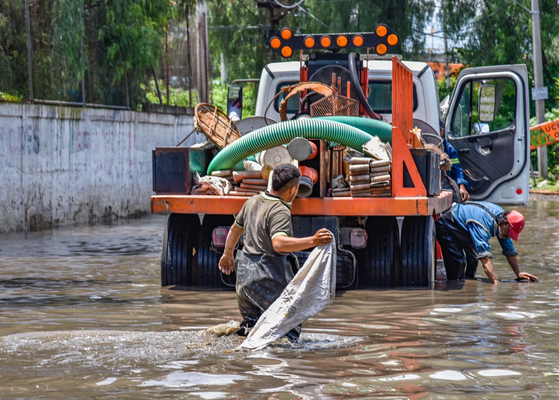 Professional flood response workers in yellow safety gear deploying emergency pumps and dehumidifiers in a Fort Worth home after storm flooding, showing the equipment GOAT brings to every emergency call