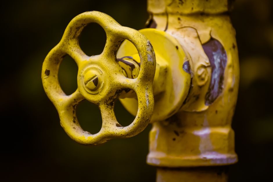 Weathered yellow gate valve handwheel on a home main water line, the kind that seizes when it is never exercised